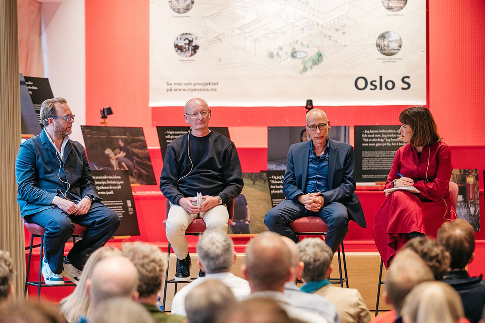 Paneldeltagerne sitter på stoler vendt mot publikum med plansjer om Nye Oslo S i bakgrunnen.